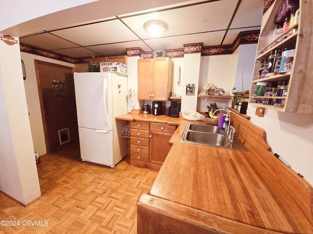 kitchen featuring light parquet floors, white fridge, a drop ceiling, and sink