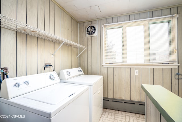 laundry area featuring wood walls, a baseboard radiator, and washing machine and dryer