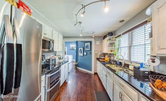 kitchen featuring rail lighting, tasteful backsplash, stainless steel appliances, and white cabinetry