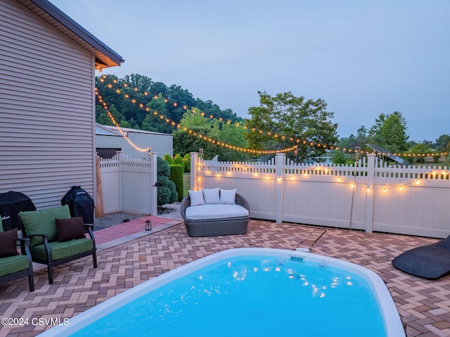 pool at dusk with a patio area