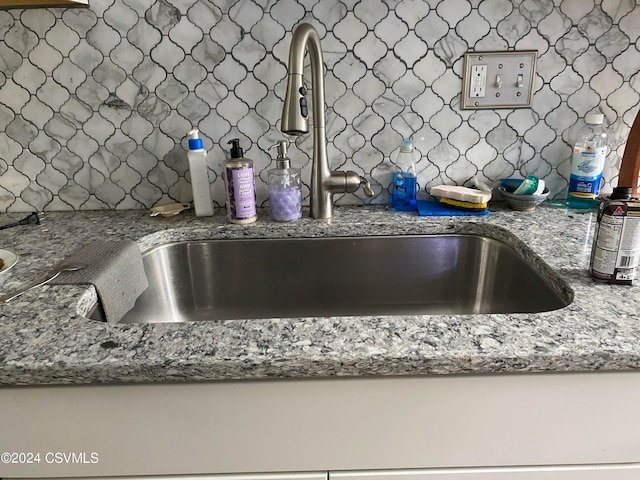 details with sink, decorative backsplash, and stone countertops