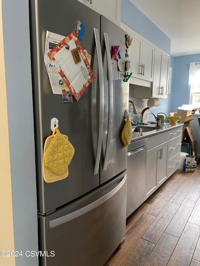 kitchen with appliances with stainless steel finishes, light hardwood / wood-style flooring, white cabinetry, and backsplash