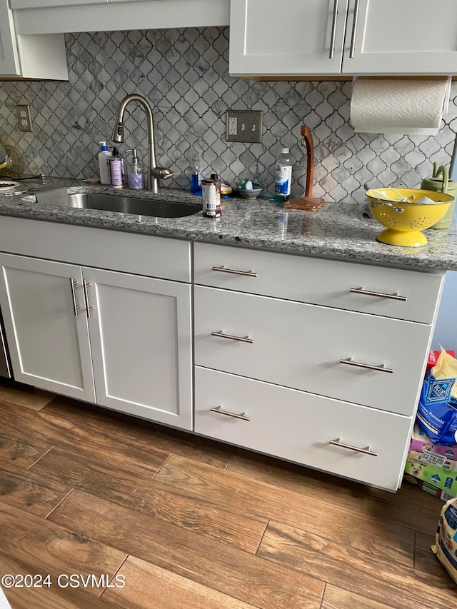 kitchen featuring sink, tasteful backsplash, stone countertops, and dark wood-type flooring