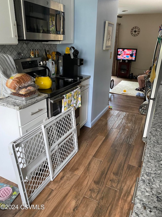 kitchen featuring white cabinetry, appliances with stainless steel finishes, dark hardwood / wood-style floors, and decorative backsplash