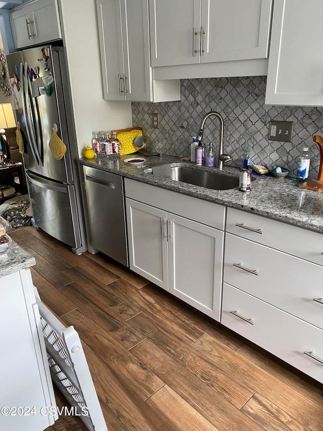 kitchen with backsplash, dark wood-type flooring, sink, stone counters, and stainless steel appliances