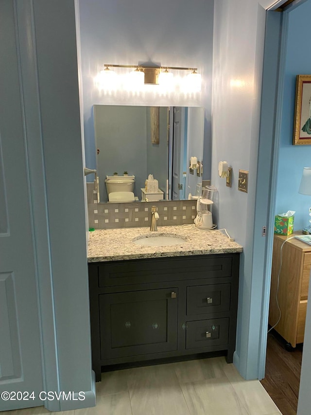 bathroom with wood-type flooring, backsplash, vanity, and toilet