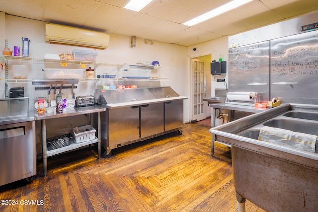 kitchen featuring a paneled ceiling, stainless steel counters, and a wall mounted air conditioner