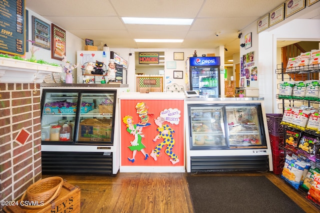 interior space featuring a paneled ceiling, beverage cooler, and wood-type flooring