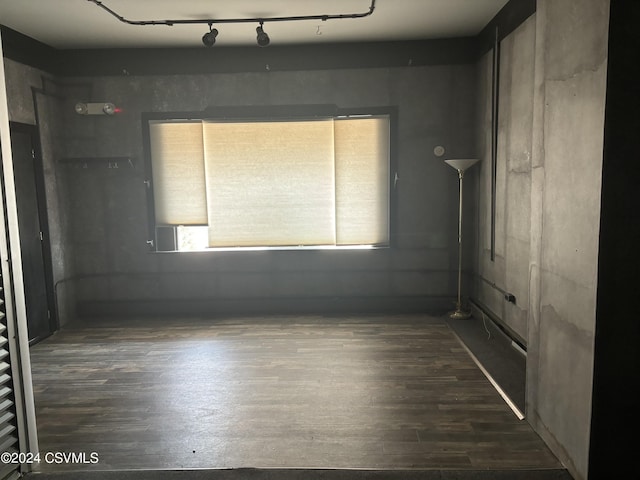 spare room featuring track lighting and dark hardwood / wood-style flooring