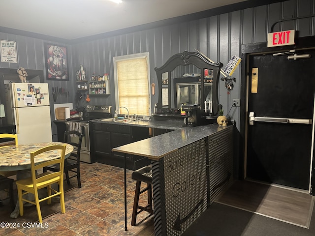 kitchen featuring white fridge, sink, black fridge, kitchen peninsula, and stainless steel range with electric cooktop