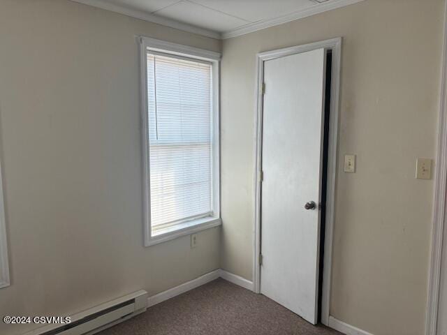 carpeted spare room with crown molding and a baseboard heating unit