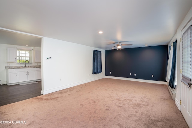 carpeted empty room with a baseboard radiator, sink, and ceiling fan