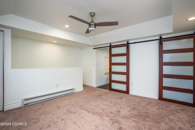 interior space with baseboard heating, ceiling fan, a barn door, and dark carpet