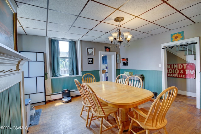 dining room with wood-type flooring, a drop ceiling, and a chandelier