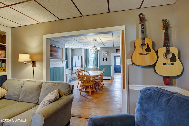 living room with a fireplace, a paneled ceiling, a chandelier, and hardwood / wood-style flooring