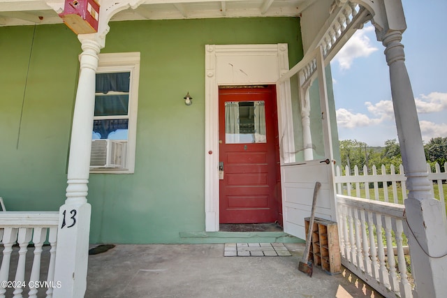 entrance to property featuring covered porch and cooling unit