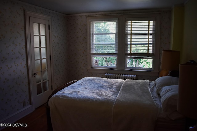 bedroom with radiator, hardwood / wood-style flooring, and multiple windows