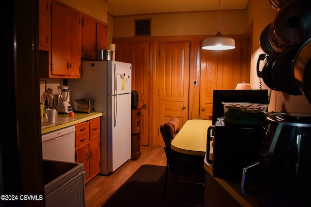 kitchen with light hardwood / wood-style flooring, white appliances, and decorative light fixtures