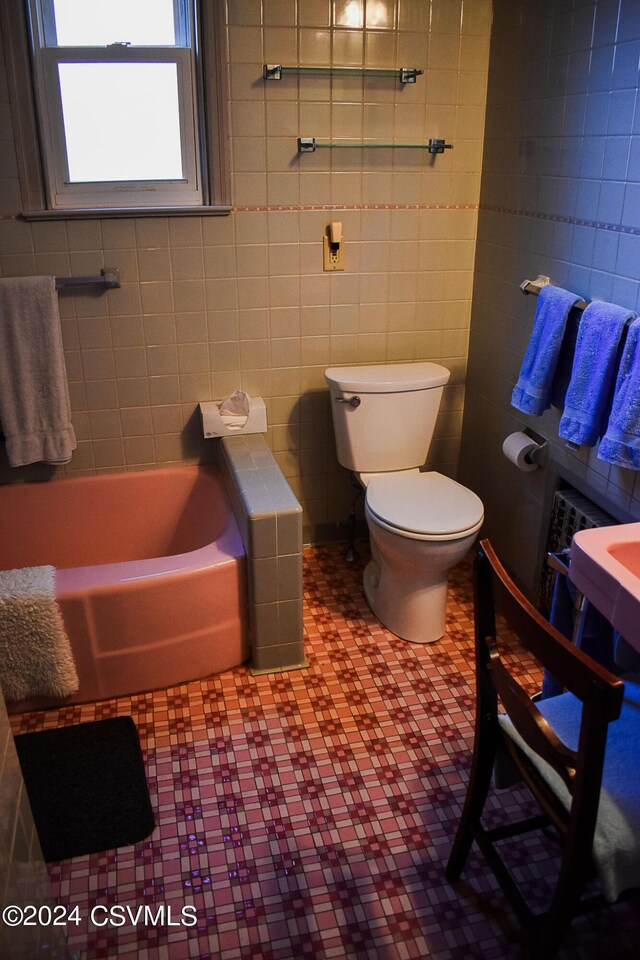 bathroom featuring tile walls, tile patterned floors, and toilet