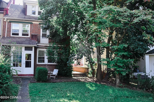 view of front of home with a balcony and a front yard