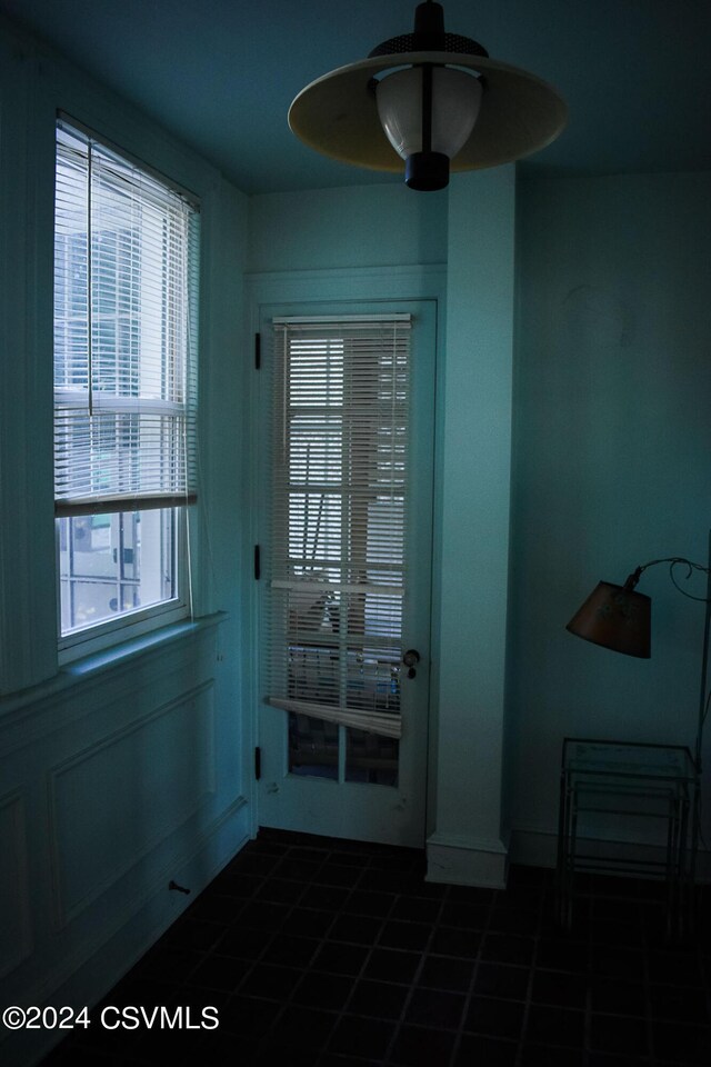 doorway to outside with ceiling fan, dark tile patterned floors, and a healthy amount of sunlight