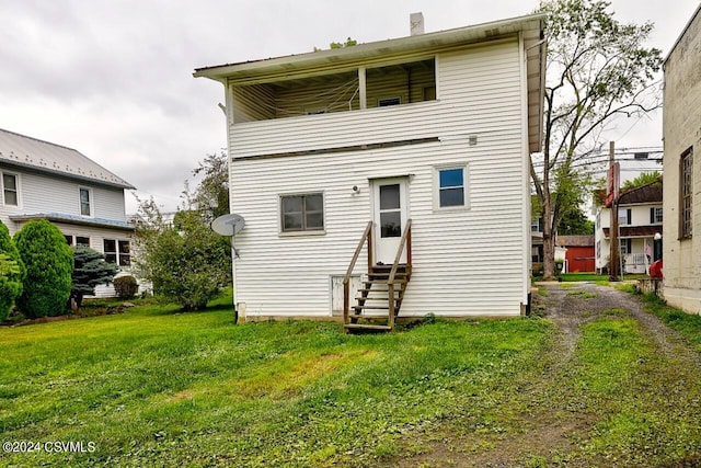 rear view of property featuring a yard and a balcony