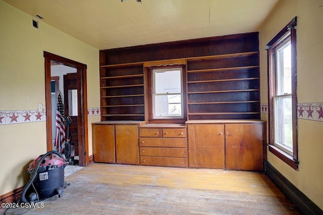 interior space featuring a baseboard heating unit, light hardwood / wood-style flooring, and built in features