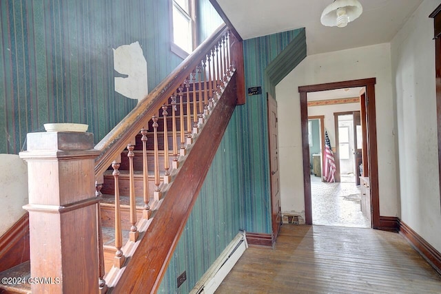 staircase featuring a baseboard heating unit and wood-type flooring