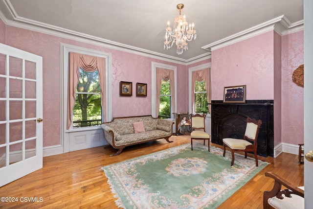 living room with hardwood / wood-style floors, an inviting chandelier, ornamental molding, and a healthy amount of sunlight