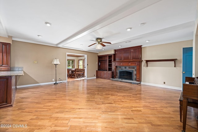 living room with ceiling fan, light hardwood / wood-style floors, beamed ceiling, and a tile fireplace