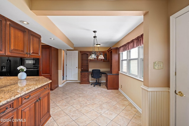 kitchen featuring light tile patterned flooring, black appliances, light stone countertops, and decorative light fixtures