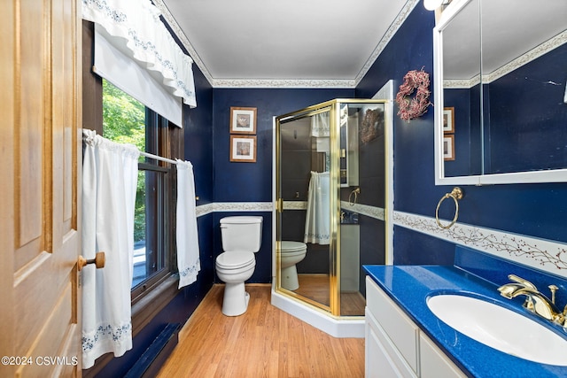 bathroom featuring hardwood / wood-style floors, a shower with shower door, vanity, crown molding, and toilet