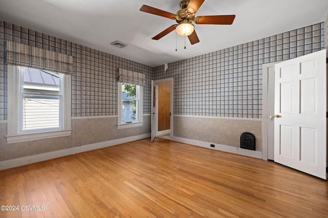 interior space with ceiling fan, light hardwood / wood-style flooring, and tile walls