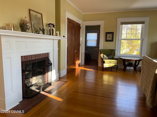 sitting room with dark wood-type flooring, crown molding, and a brick fireplace