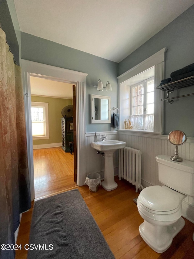 bathroom with toilet, radiator heating unit, and hardwood / wood-style floors