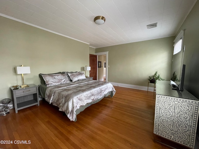 bedroom with dark wood-type flooring and crown molding