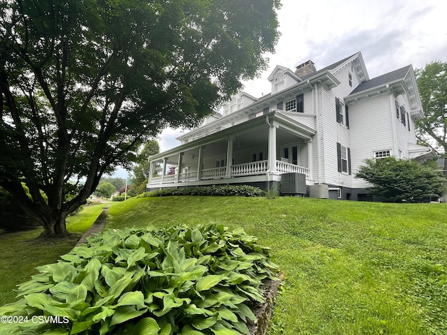 view of side of property with covered porch and a yard