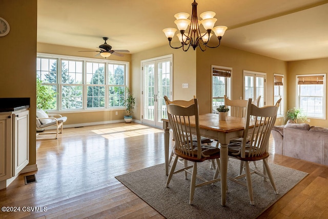 dining area with light hardwood / wood-style floors, ceiling fan with notable chandelier, and french doors