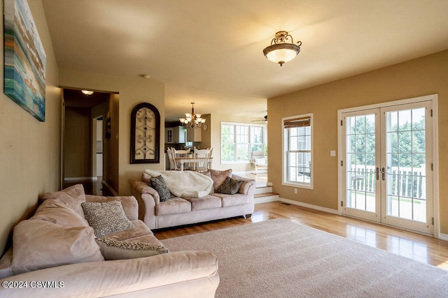 living room featuring light hardwood / wood-style floors, french doors, and a chandelier