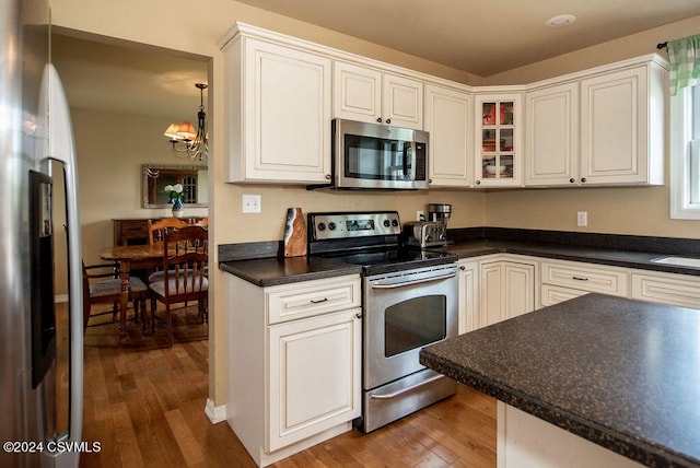 kitchen featuring decorative light fixtures, appliances with stainless steel finishes, a chandelier, light hardwood / wood-style floors, and white cabinetry