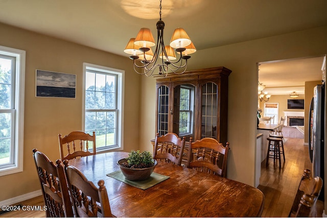 dining space featuring wood-type flooring, a healthy amount of sunlight, and a chandelier