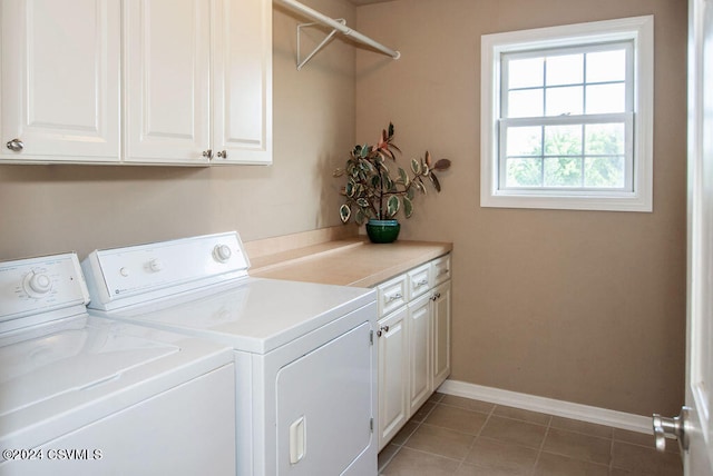 clothes washing area with washing machine and clothes dryer, tile patterned flooring, and cabinets