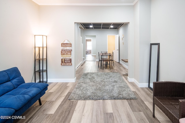 sitting room with crown molding and light hardwood / wood-style flooring