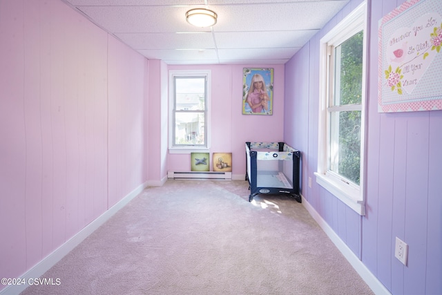 unfurnished bedroom with multiple windows, carpet, and a drop ceiling