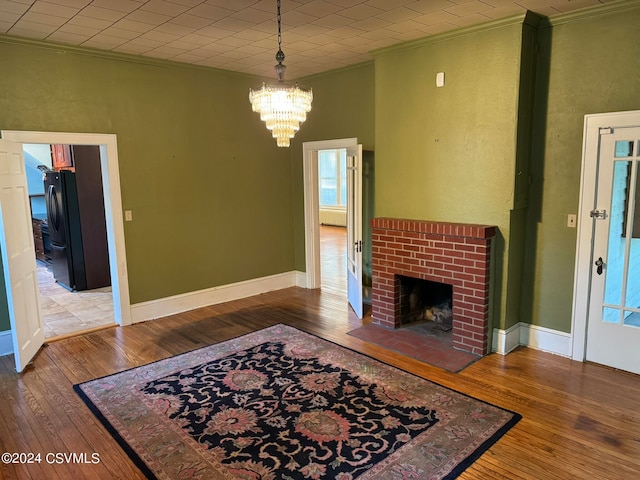 living room with crown molding, hardwood / wood-style flooring, a notable chandelier, and a fireplace