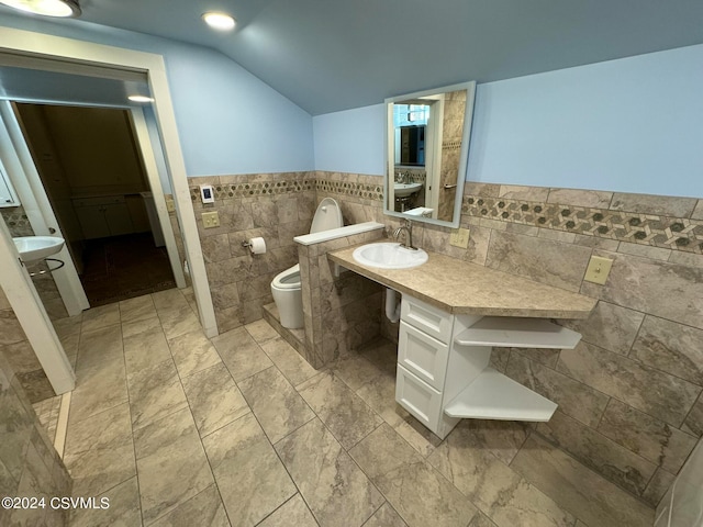 bathroom with vanity, toilet, tile walls, and vaulted ceiling