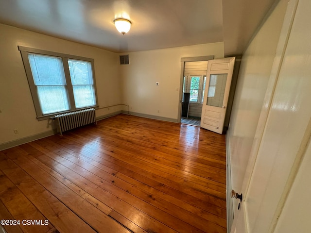 unfurnished room with plenty of natural light, hardwood / wood-style floors, and radiator