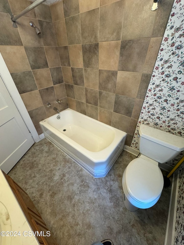 bathroom featuring toilet, tile walls, and tiled shower / bath