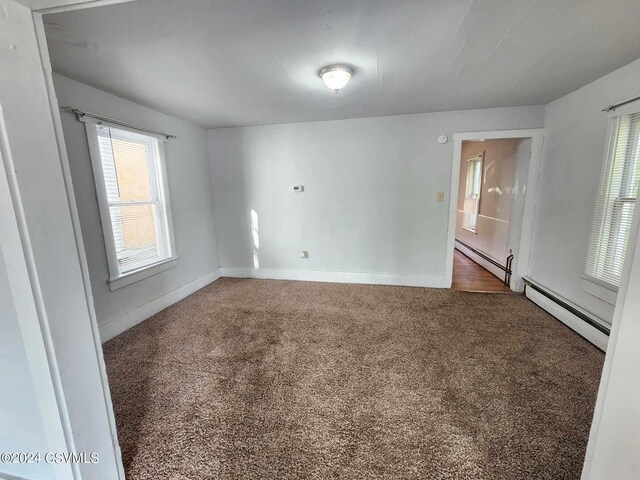 unfurnished room featuring a baseboard heating unit and carpet flooring