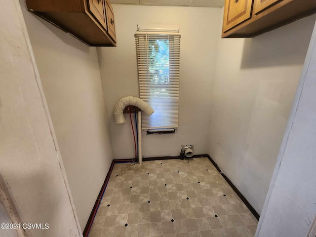 clothes washing area with light tile patterned floors and cabinets